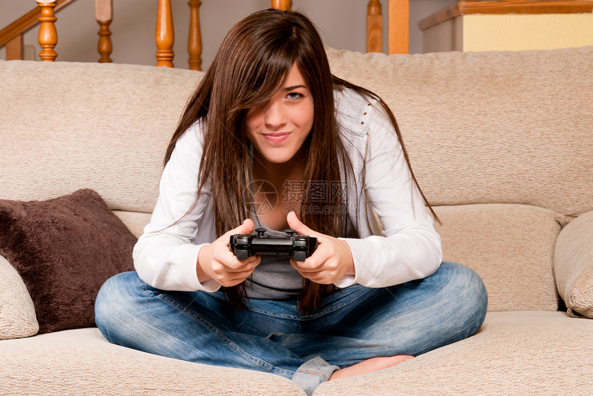 在家沙发上玩视频游戏的年轻女性专注微笑喜悦幸福黑发女士闲暇电子游戏娱乐安慰挑战图片