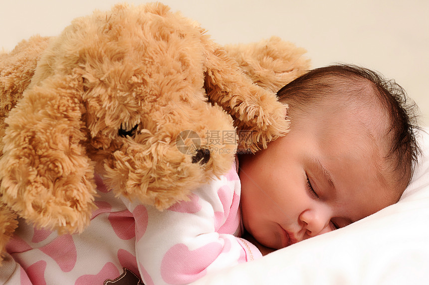 婴儿背着棕色玩具狗睡觉图片