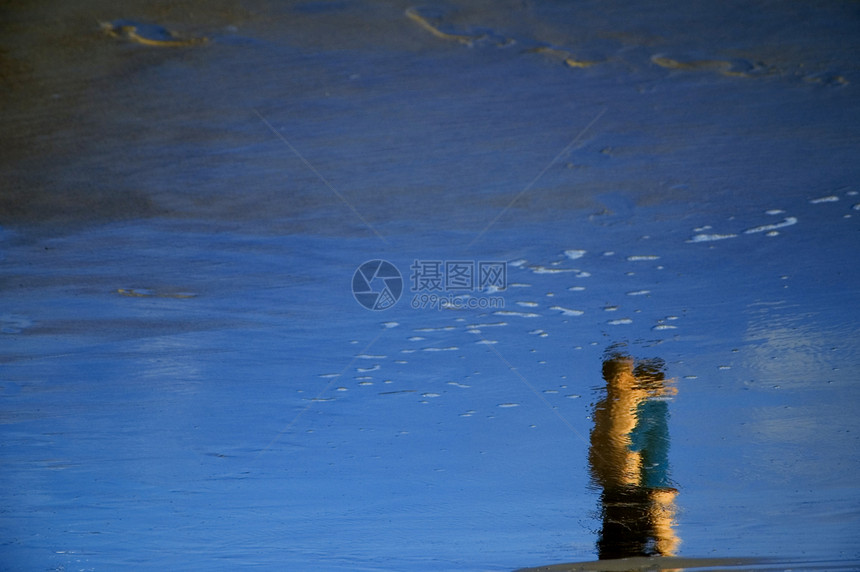 在海滩上黄色蓝色镜子女士男人反射波浪白色石头图片