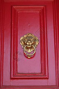 狮子门敲进器青铜狮子木头金属红色入口金子黄铜背景图片