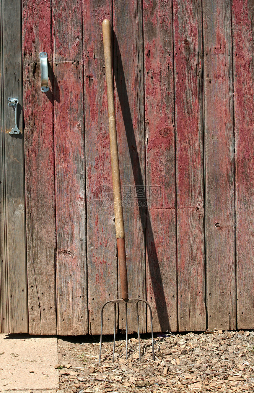 爬在旧红色谷仓的草叉上工具木头图片