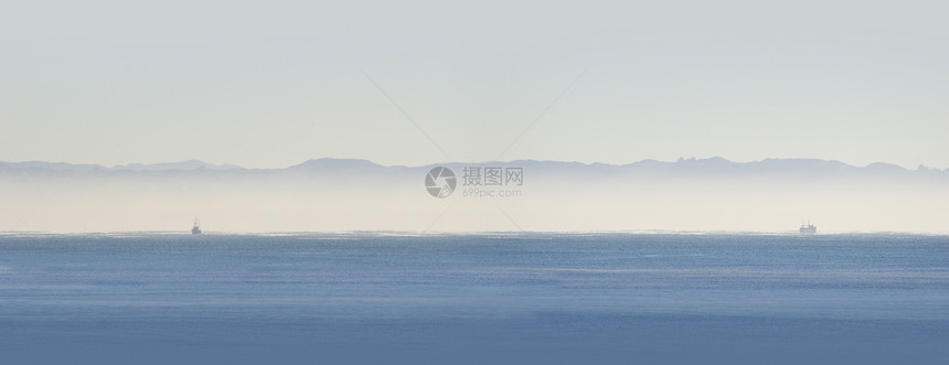 两艘渔船全景海洋海岸丘陵天空薄雾图片