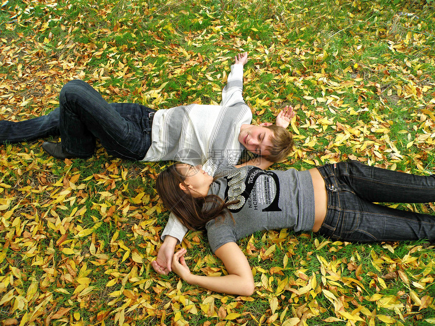 秋天公园的年轻夫妇树木衣服夹克女孩幸福微笑公园落叶长发树叶图片