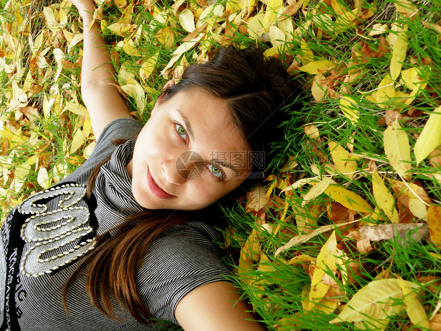 秋天公园的年轻女孩小姐夹克天鹅绒黄色绿色休息裤子树叶毛衣季节图片