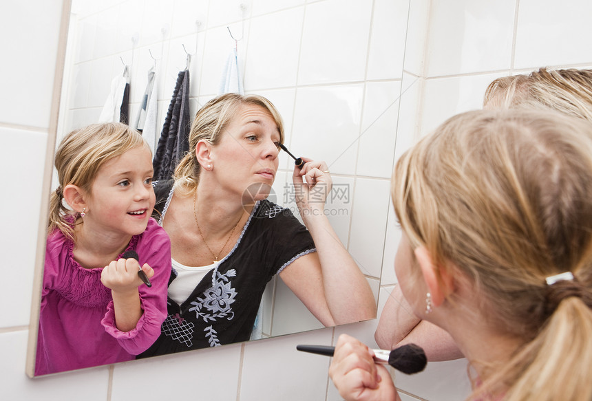 母亲和女儿都化妆了睫毛膏镜子反射口红小女孩化妆品女性家庭白色浴室图片