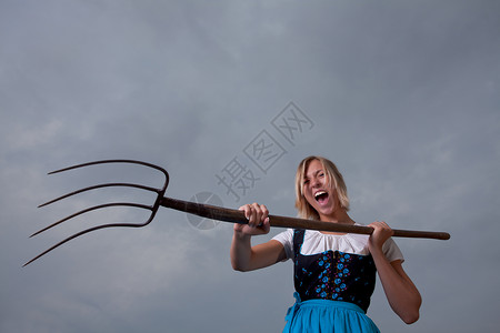 充满愤怒的巴伐利亚女孩和草叉高清图片