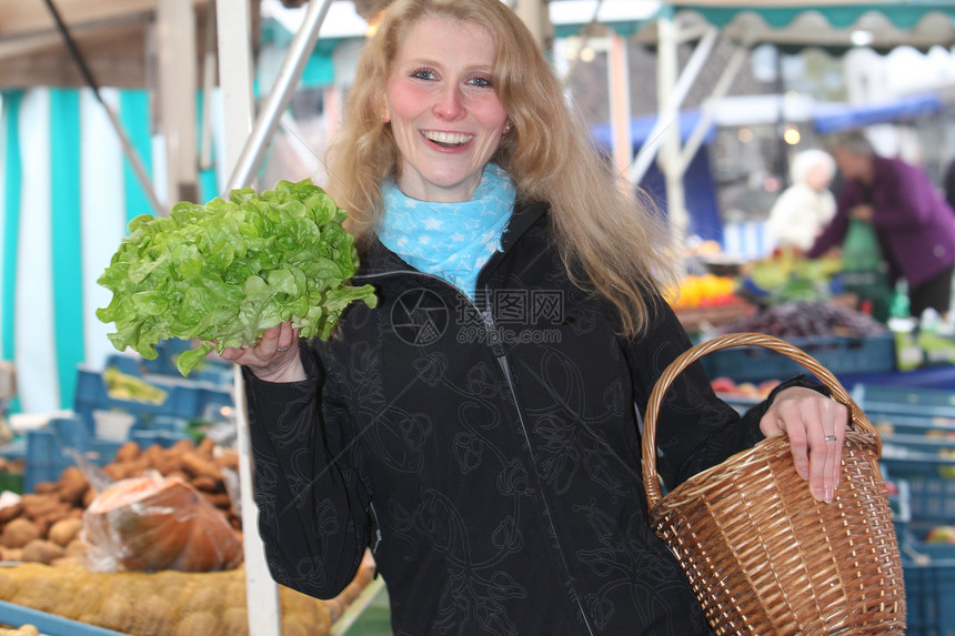 在市场上笑着的女人 买新鲜沙拉图片