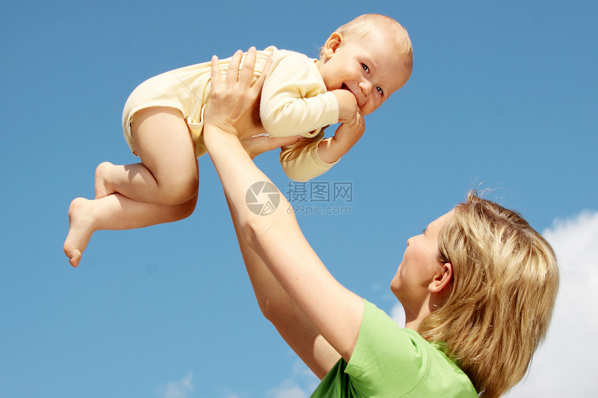 母亲在蓝天下怀着婴儿拥抱儿子父母女士母性女性微笑童年家庭女孩图片
