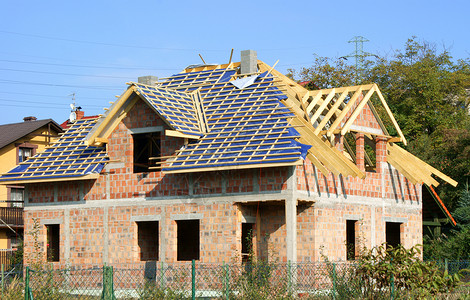 正在建造中的新住宅房建筑勃起开发商蓝色隐藏窗户房子天空背景图片