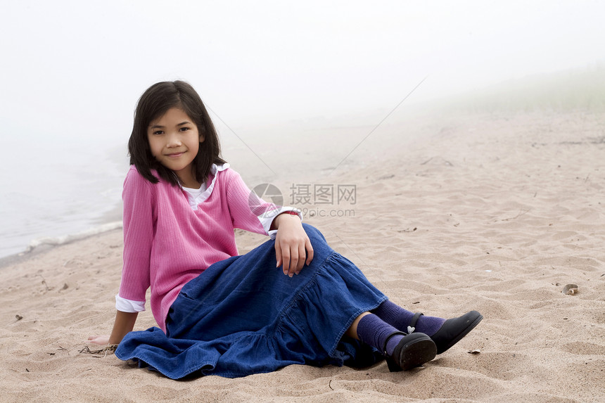 坐在沙滩上的年轻女孩空气牛仔布混血海洋福利海滩支撑裙子倾斜混血儿图片