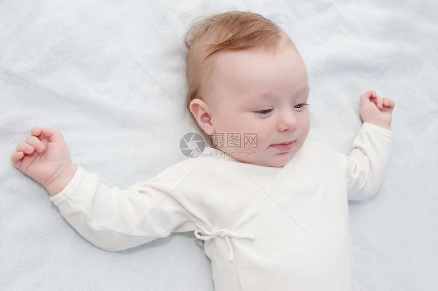 婴儿男孩躺在床上冒充工作室新生展示孩子白色红色生活毯子丝带图片
