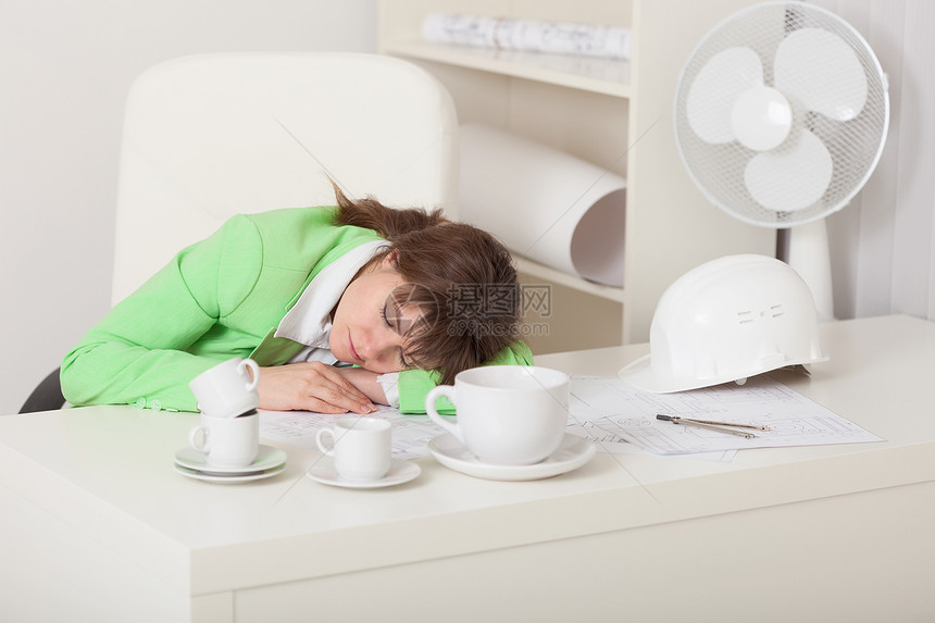 商业妇女睡在工作场所的桌子上;图片