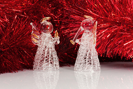 两个玻璃天使和圣诞树锡罐新年白色金子玩具喇叭翅膀反射雨云红色亮片背景图片
