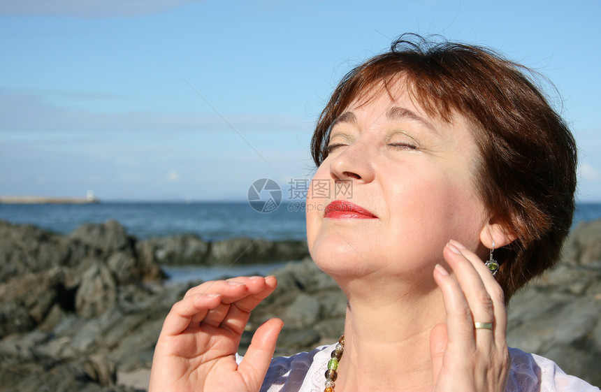 女士在沙滩上黑发首饰岩石太阳海滩海岸线晴天女性微笑乐趣图片