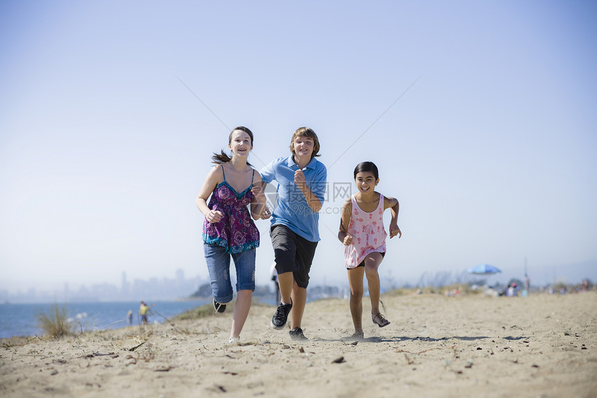 三个孩子跑在海滩上男生青年蓝天团体混血少年运动友谊活力青少年图片