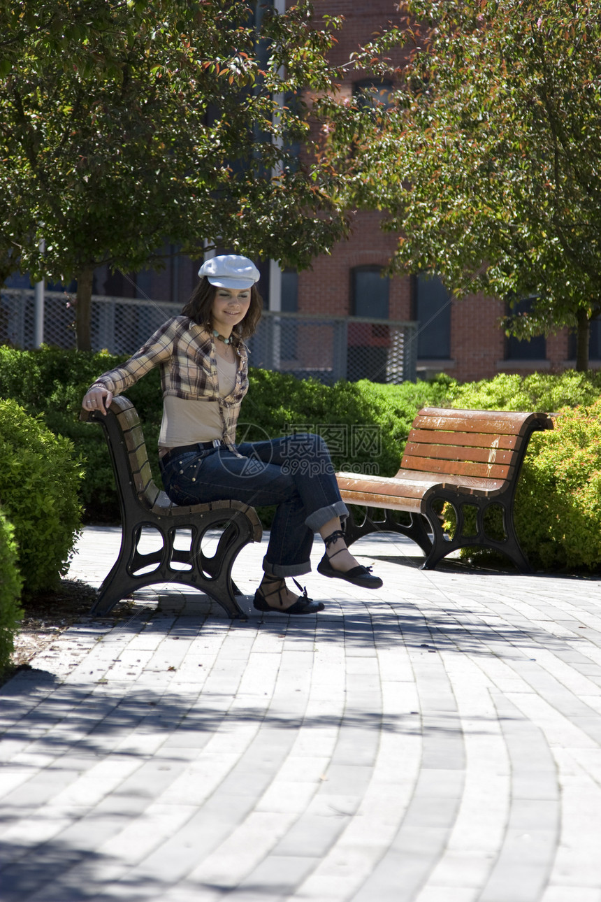 坐在公园里的女孩女性青少年人行道树木长椅晴天黑发孤独路面学生图片