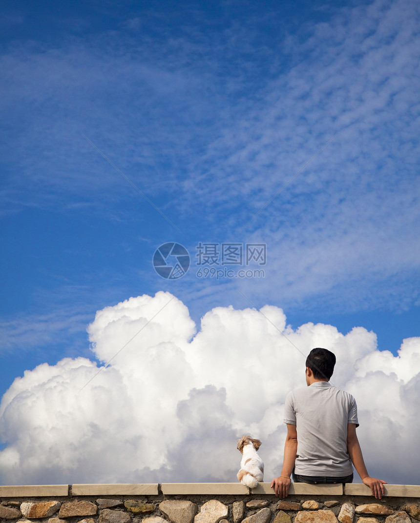 男人和狗坐在一起 看着夏天的云朵图片