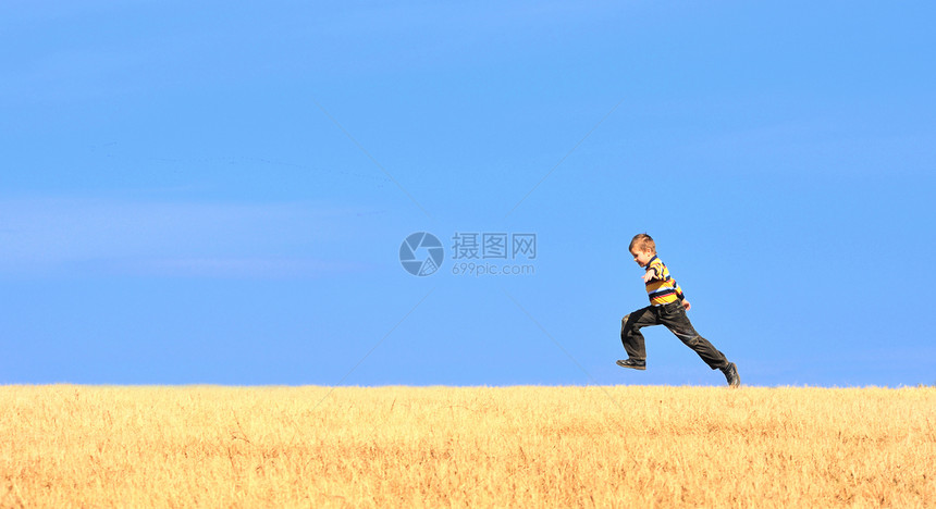 年轻男孩在田野上跳跃牛仔裤天空青年蓝色草地自由休闲幸福土地跑步图片