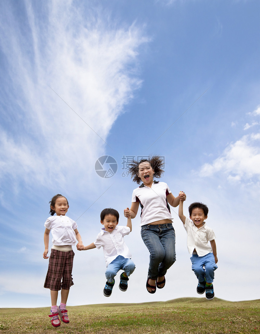 快乐的亚洲家庭在草地上跳跃图片