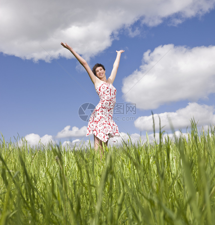 站在田野上的年轻女性日光浴微笑快乐幸福休闲阳光天空福利成人喜悦图片