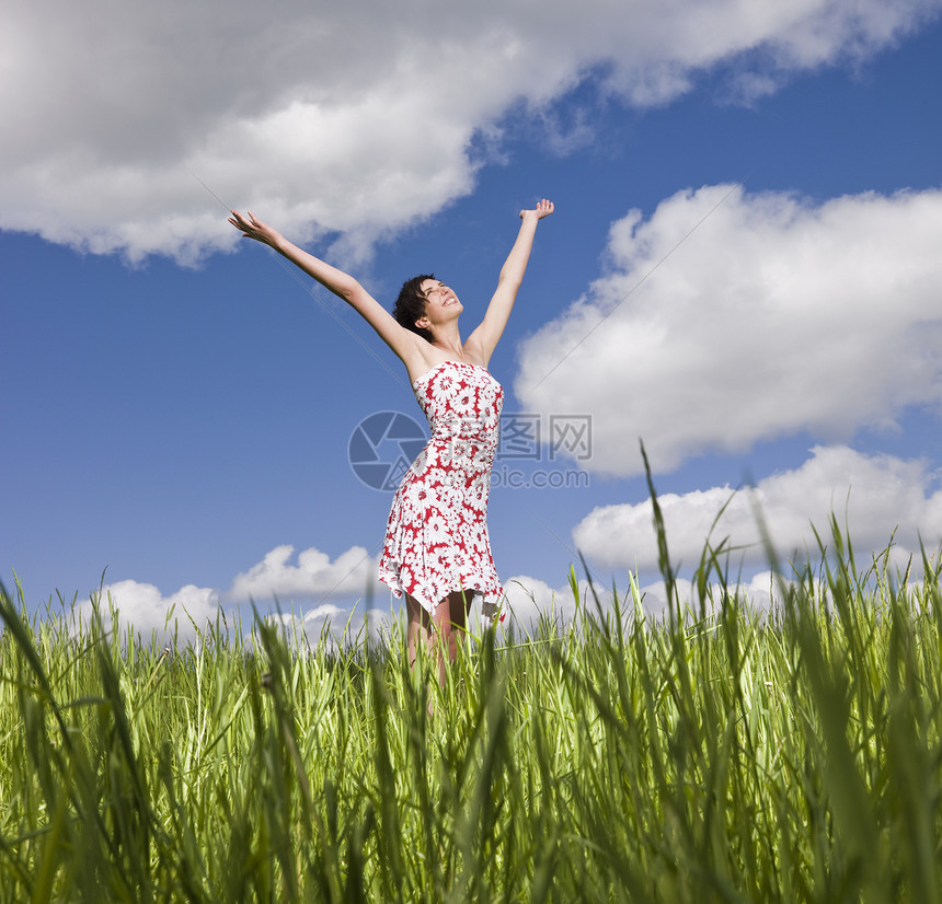 站在田野上的年轻女性双臂微笑蓝色服装护理日光浴福利面积草地快乐图片