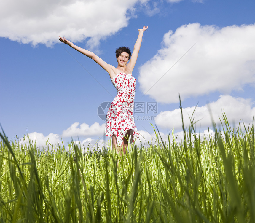年轻女子举起双臂站在田地上成人草地阳光天空女性身体幸福自由福利图片