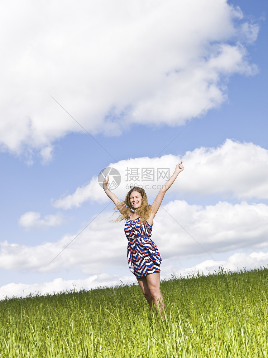 站在田野上的年轻女性身体手臂服装活力草地双臂微笑阳光日光浴成人图片