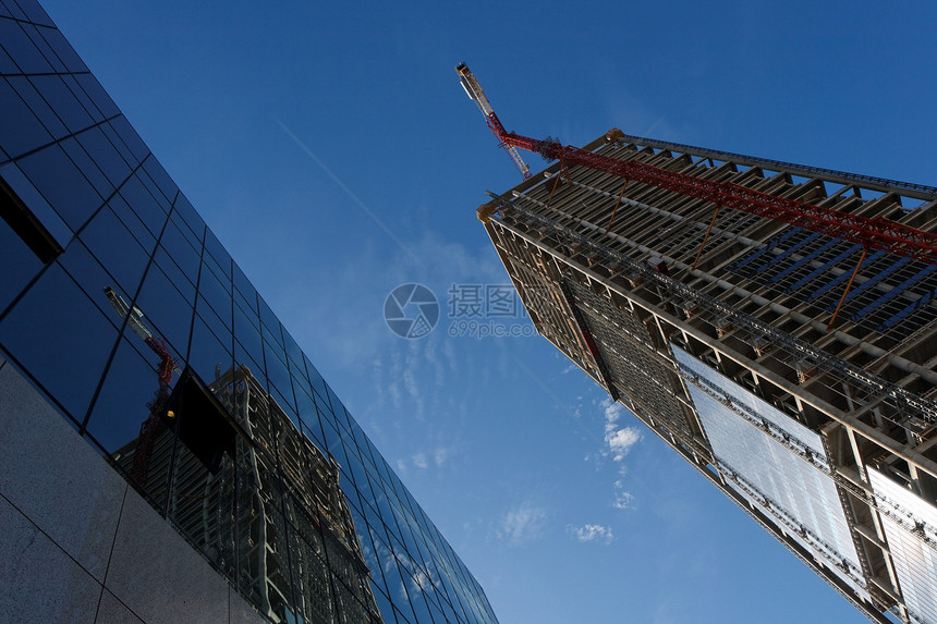 正在建造的起重吊机和高楼 反映在另一栋大楼中图片