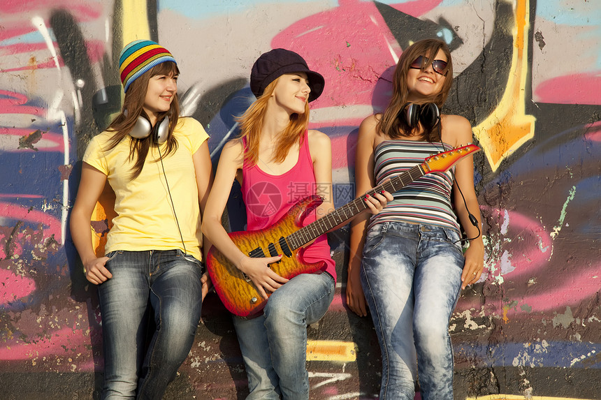 三个美丽的女孩 带着吉他和涂鸦墙 在背角青年喜悦女性女士岩石青少年微笑城市乐趣朋友们图片