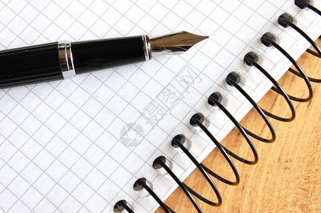 写螺旋钢笔木头笔记本喷泉笔记日历桌子墨水铅笔床单空白背景
