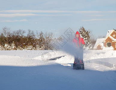 男子在雪车上使用吹雪机红色投掷者夹克男人暴风雪机器天气鼓风机风暴男性背景图片