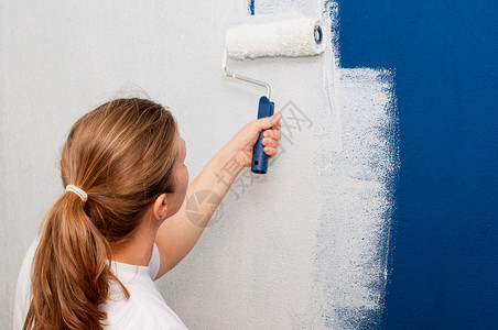 妇女画墙滚筒绘画装修画家白色房子修理房间成人蓝色背景图片