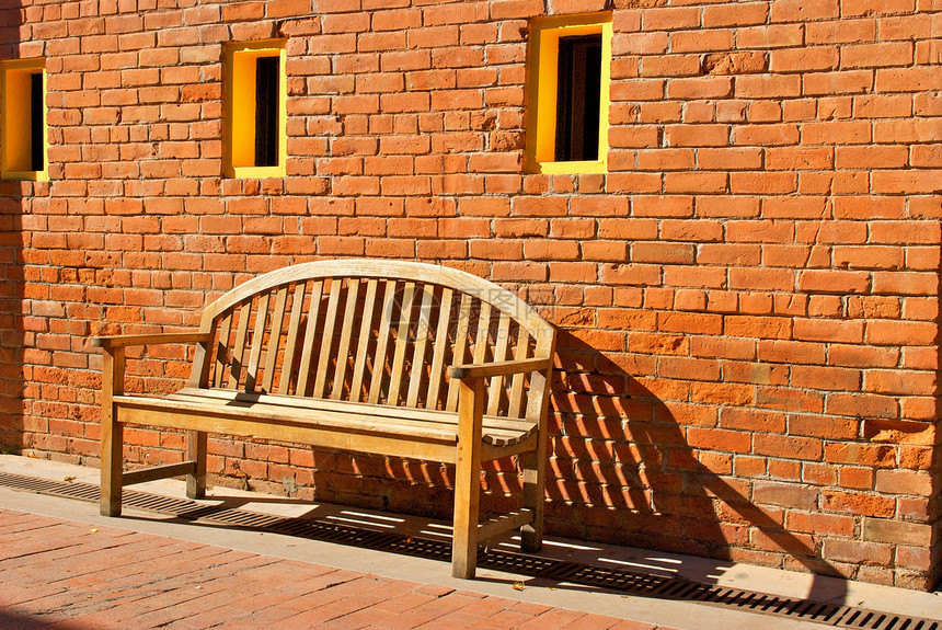 由橙砖墙和黄窗坐在木座上图片