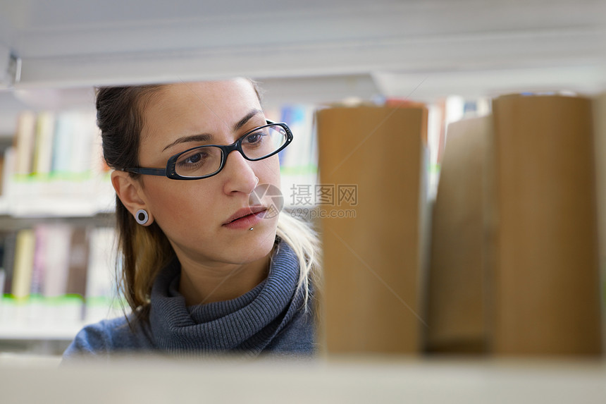 女性在库中选择书籍图书馆阅读背景架子沉思组织成人女士长发眼镜图片