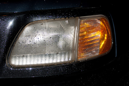 随水喷洒的雨点照亮头部头灯金属大灯光束玻璃黑色汽车黄色反射车辆背景图片