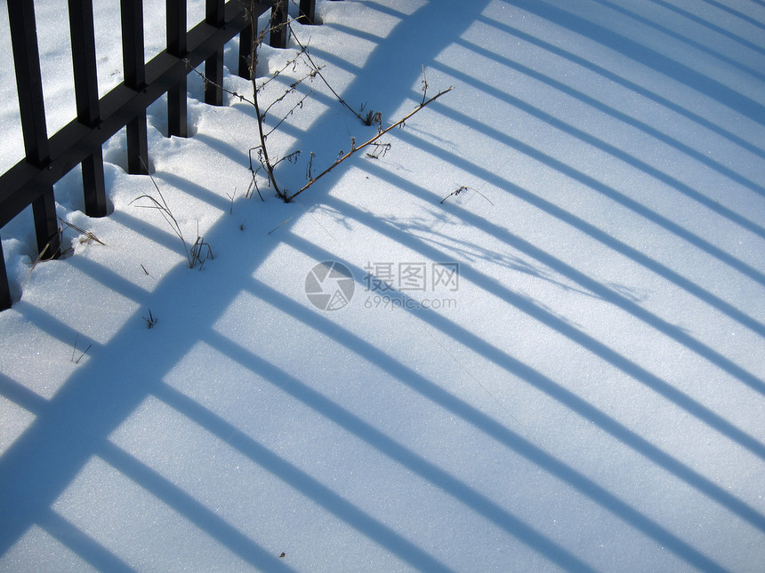 白雪上的栅栏阴影图片
