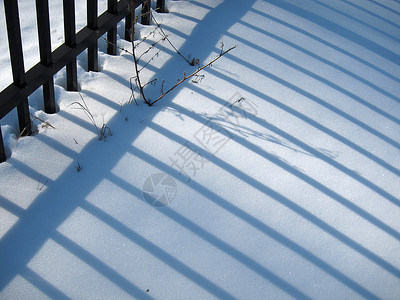 白雪上的栅栏阴影背景图片