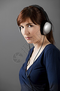 听音乐享受成人手机耳机女孩娱乐音乐灰色闲暇女性背景图片