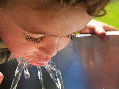 男孩从饮用水喷泉里喝水背景图片