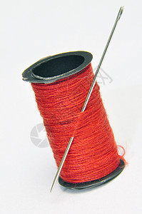 针线和针线池红色工具缝纫卷轴白色棉布背景图片