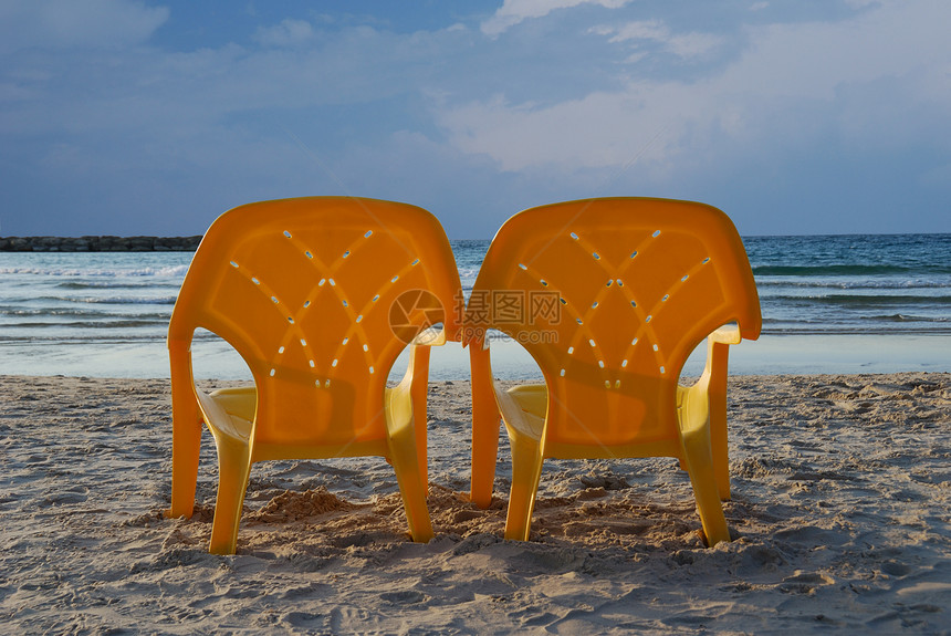 几张塑料沙滩椅面对海面图片