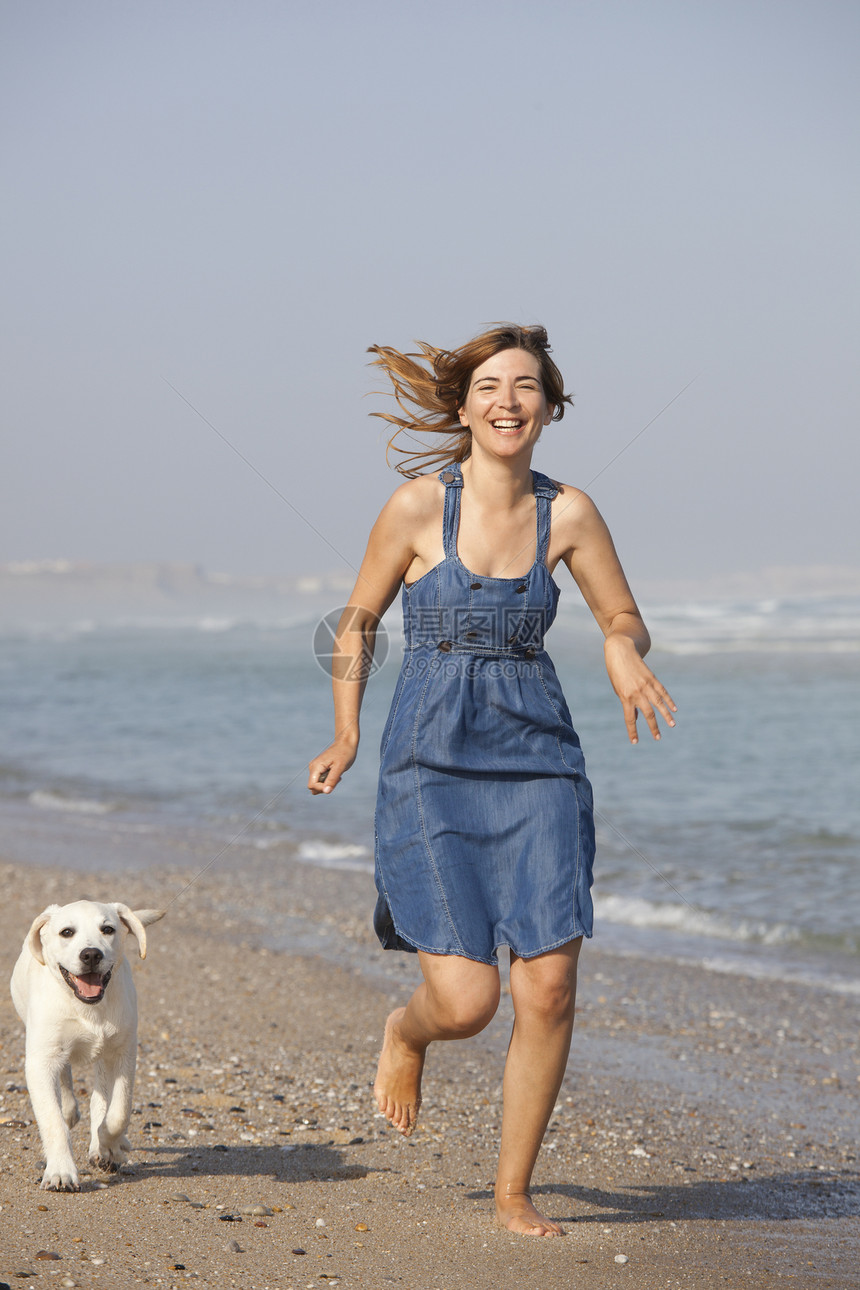 女孩带着她的狗动物海岸微笑闲暇跑步海洋猎犬宠物海滩朋友图片