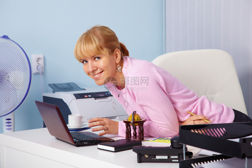 美丽的笑着微笑的年轻女孩在办公室里图片