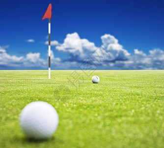 高尔夫球在背景中挂着旗子的绿色 非常浅的田地深度高清图片