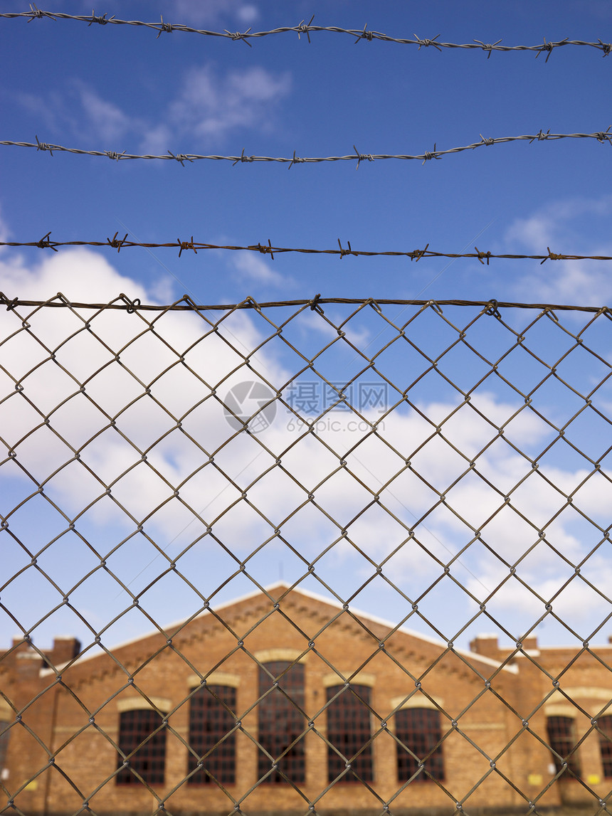 在围栏后面建筑蓝色监狱红色砖墙蓝天工业锁定栅栏图片