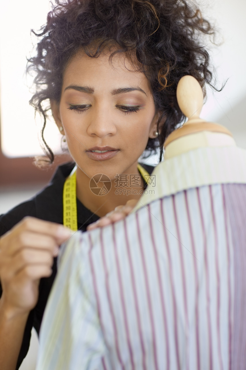 在时装设计室工作的妇女卷曲衣服工作室女性人体职场磁带测量裁缝剪裁图片