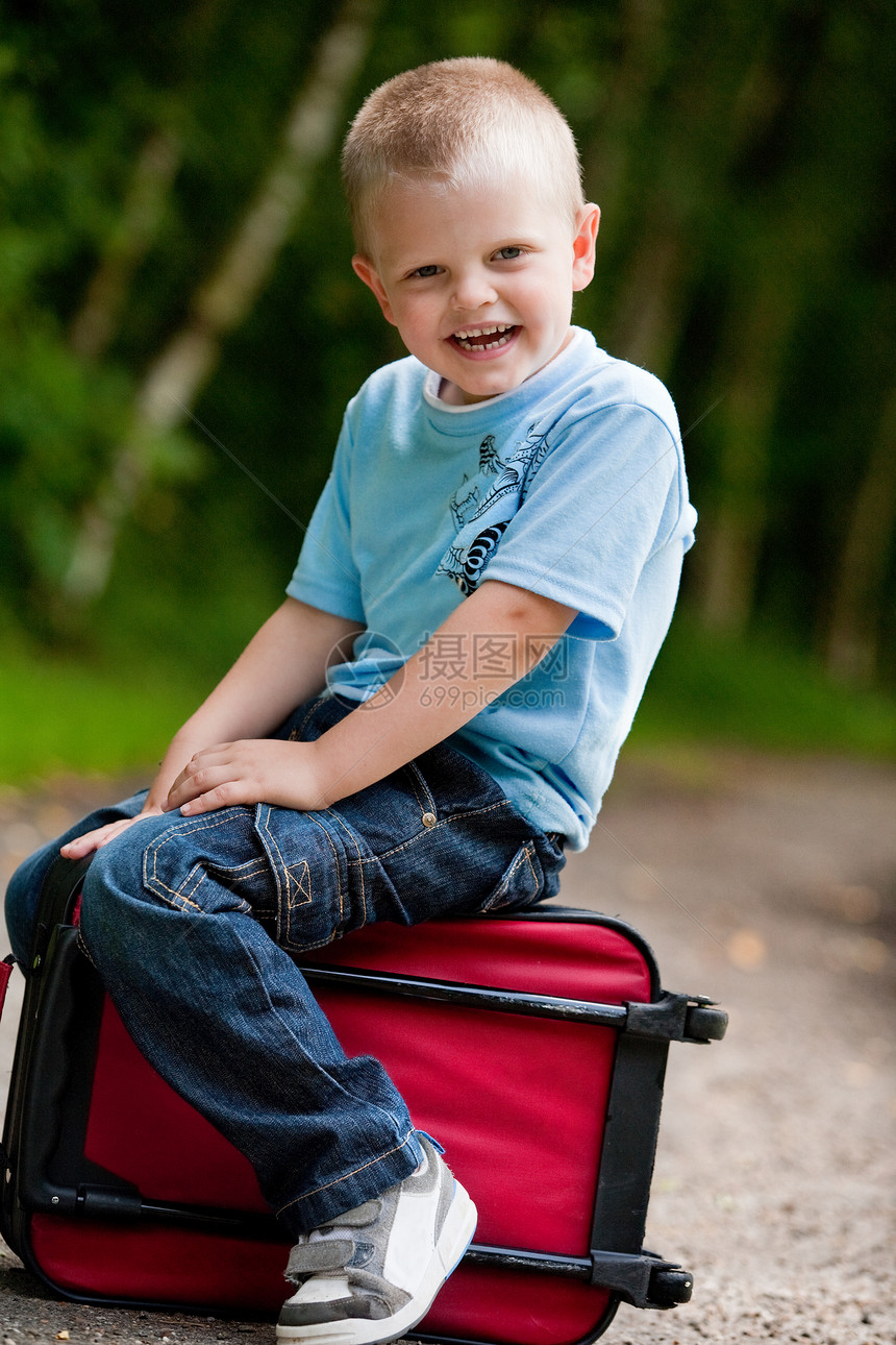坐在手提箱上的小男孩公园童年旅行快乐假期孩子全身乐趣图片