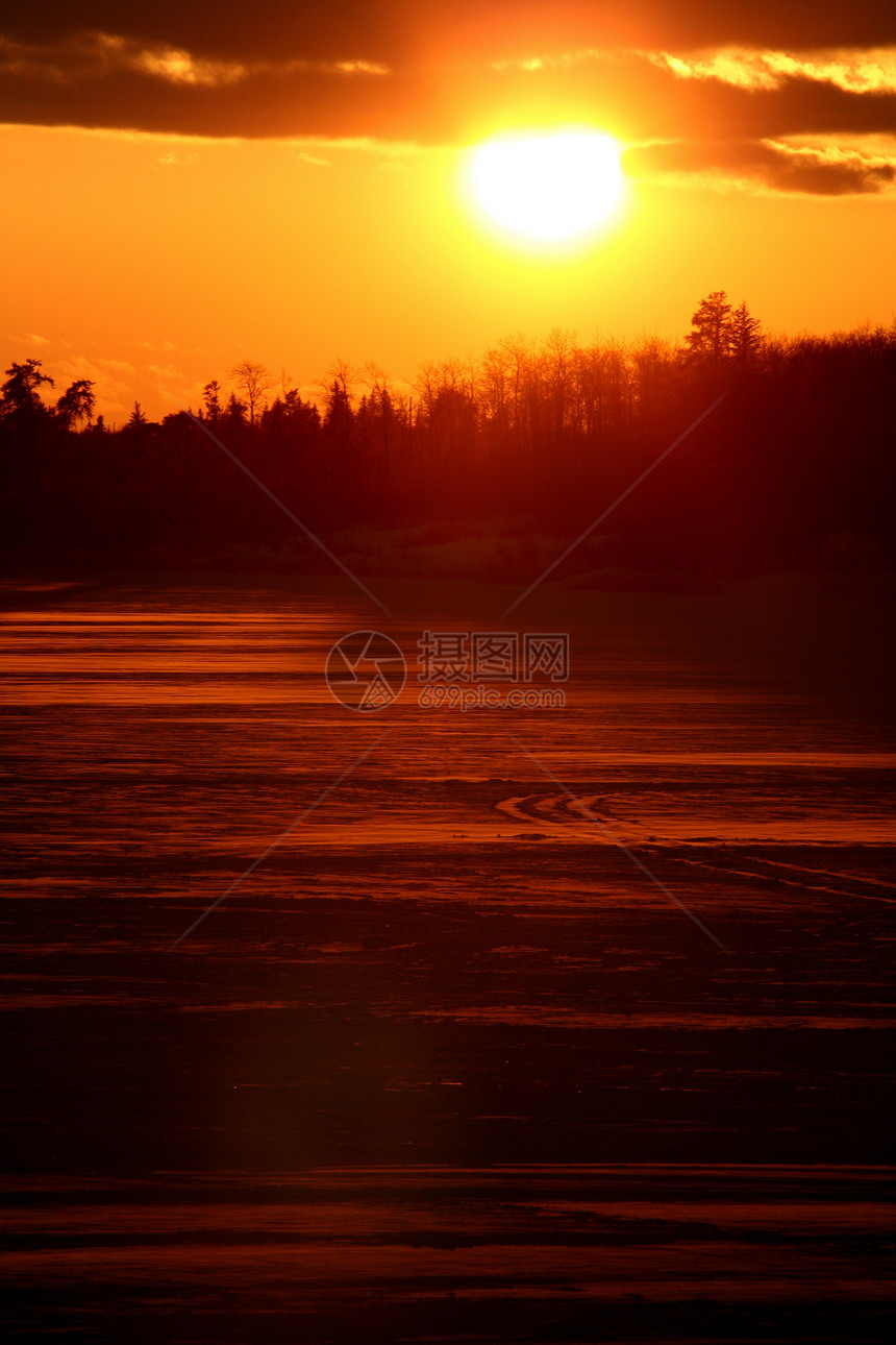 太阳落在一个冰冻的萨斯喀彻温湖后面乡村剪影树木大草原风景美术旅行图片