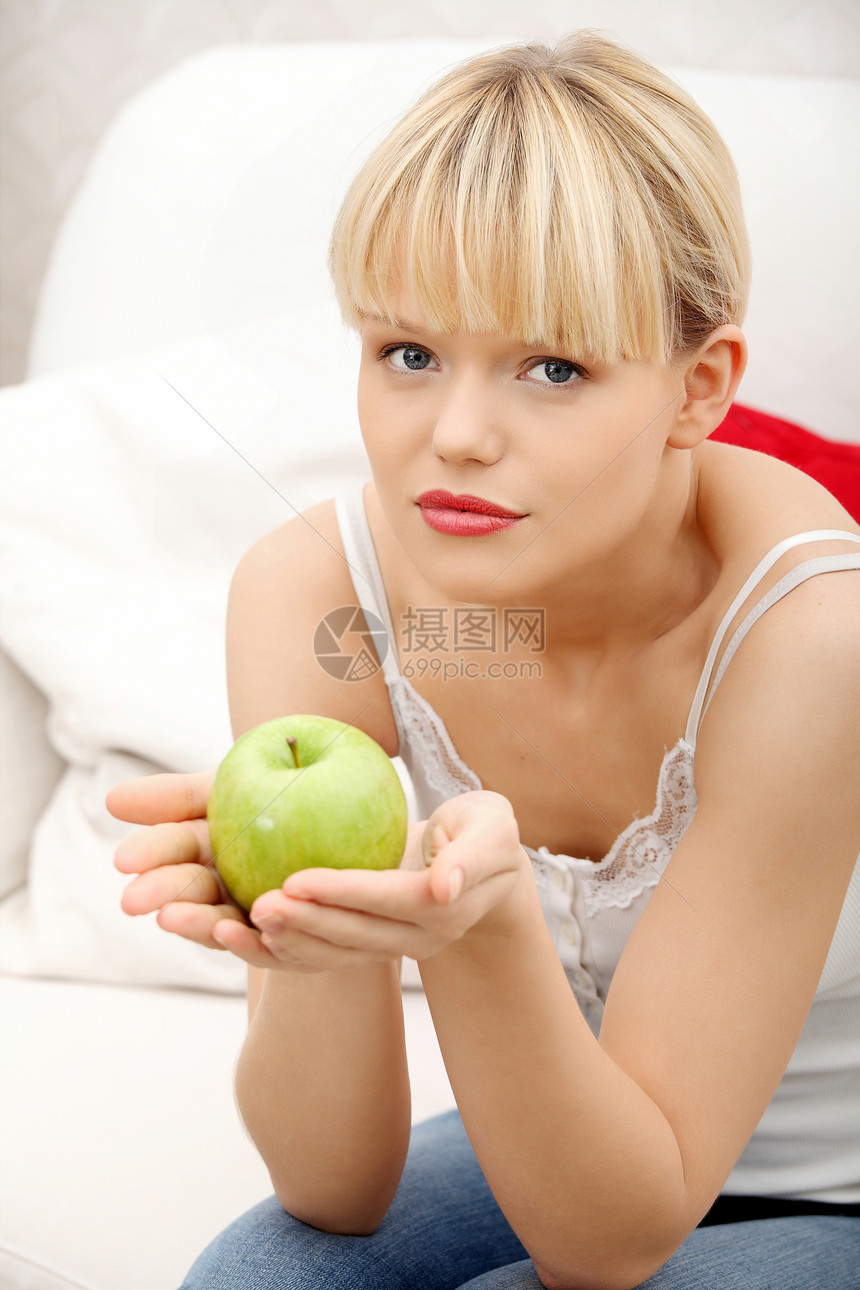 沙发上美丽的女人拿着苹果图片