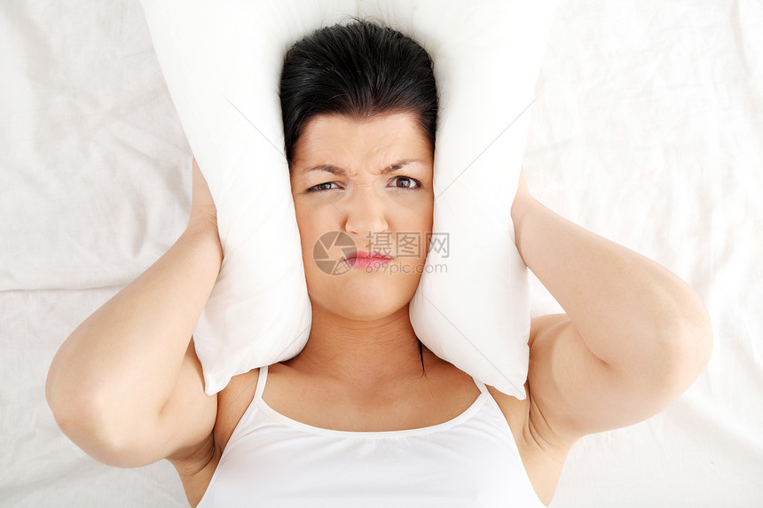 女人躺在床上 用枕头闭着耳朵压力挫折成人悲伤失眠苏醒沮丧女性噪音女孩图片